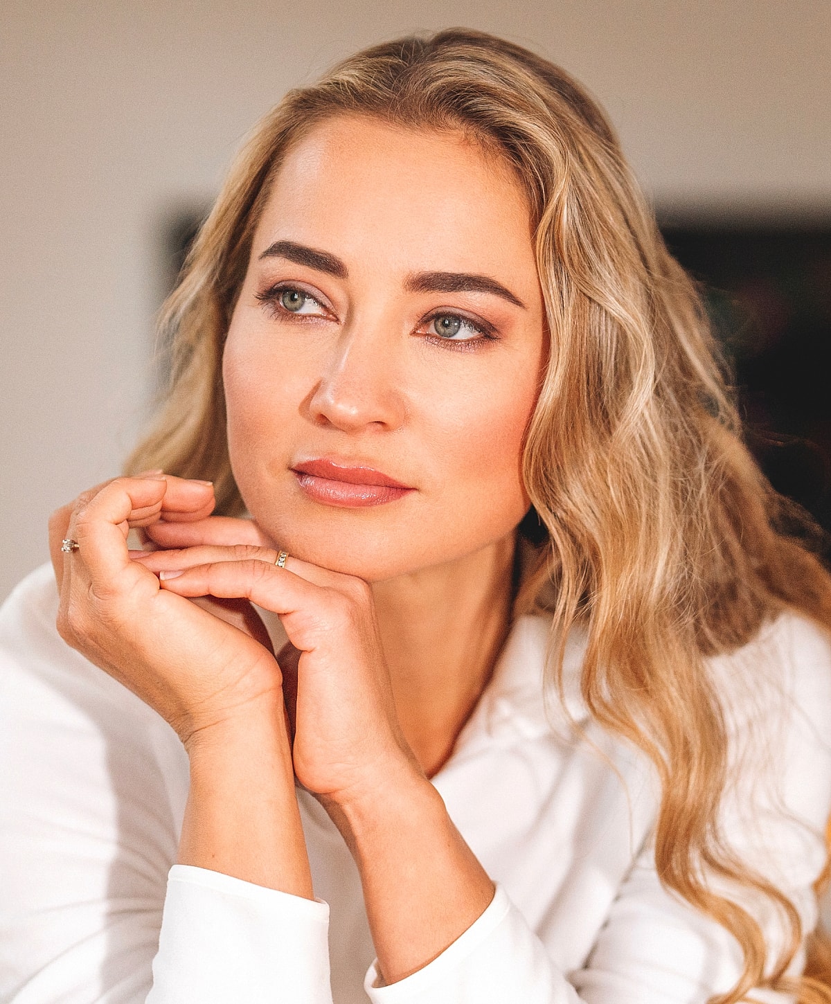 Woman with long blonde hair in thoughtful pose.