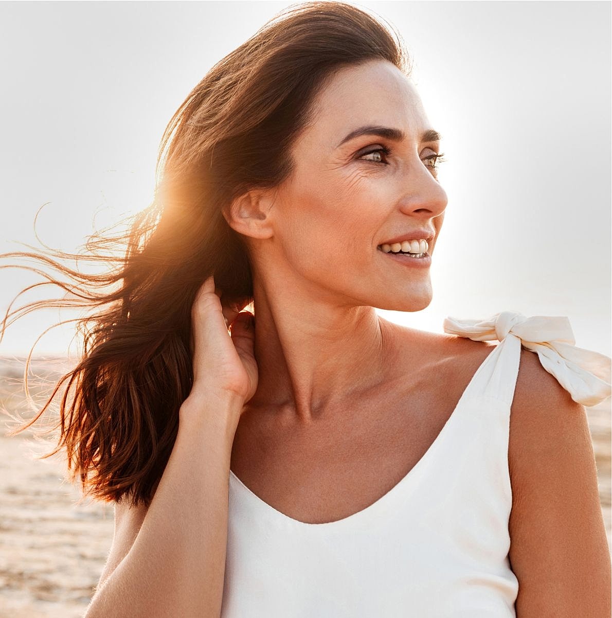 Smiling woman with flowing hair in sunlight.