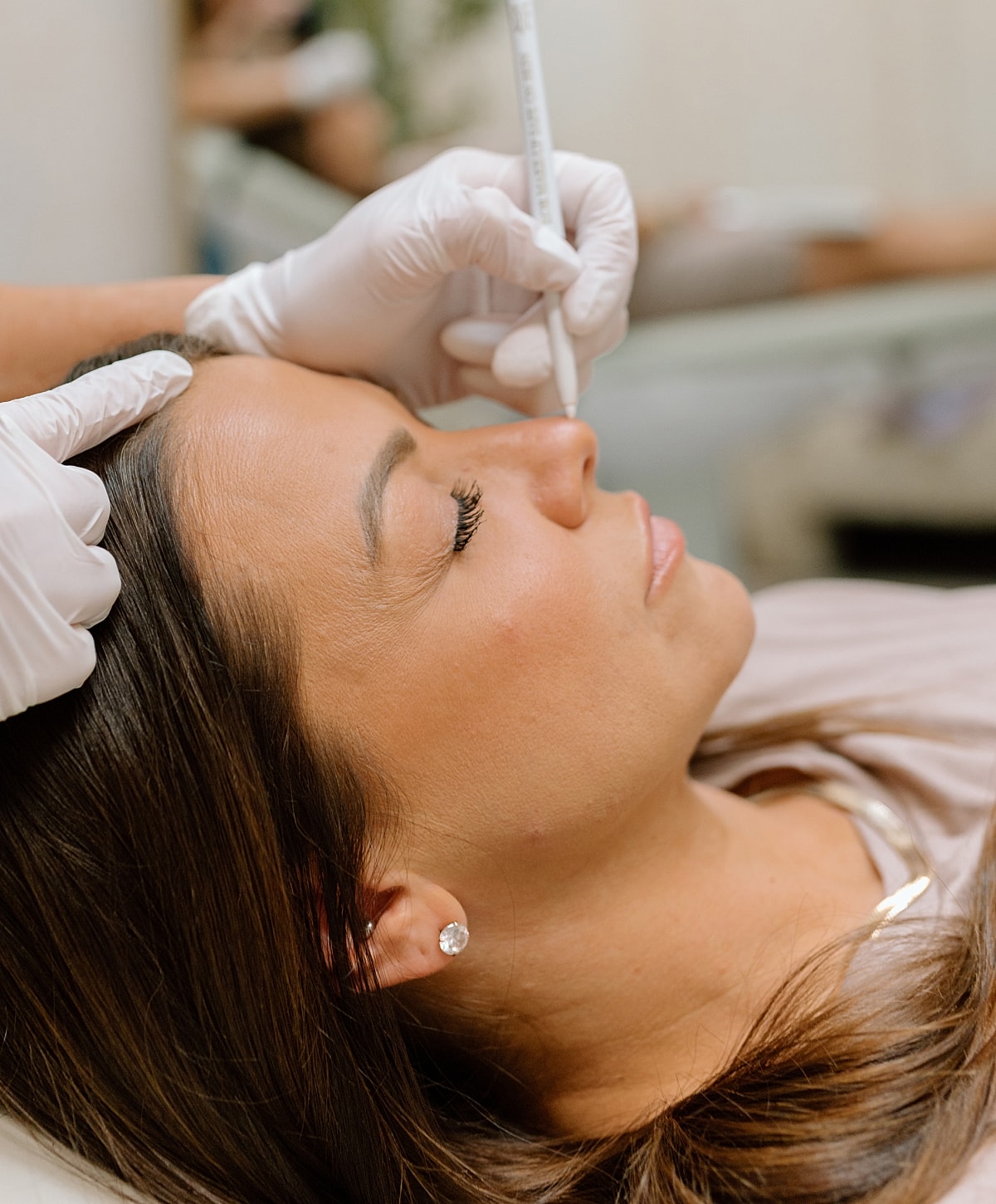 Woman receiving a cosmetic treatment with white gloves.